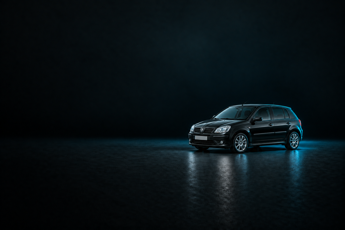 Black Renault Clio hatchback on a dark charcoal floor with cool blue lighting.