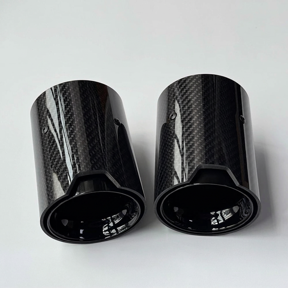 Glossy carbon fibre exhaust tips on a grey background without branding